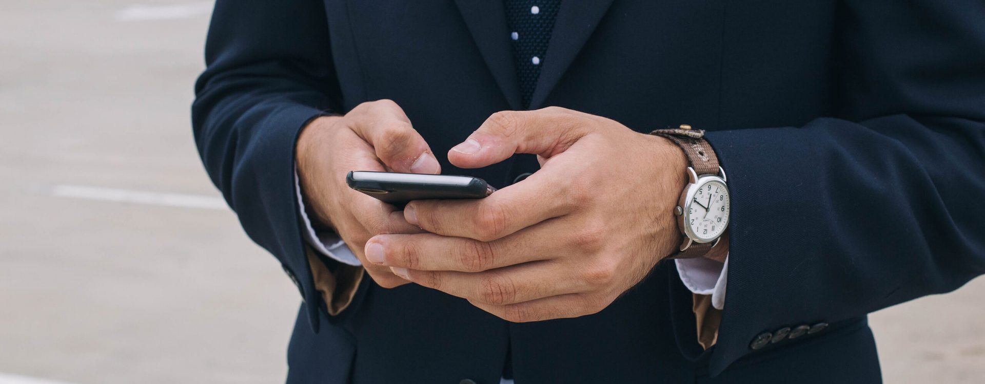 A close up of business person’s hands typing on a cell phone.