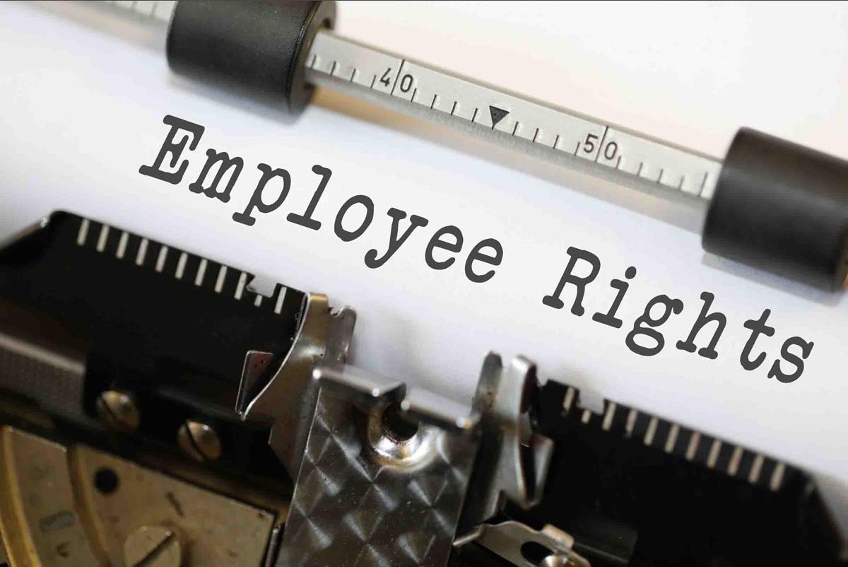 A close up image of a piece of paper secured to the platen of an old fashioned typewriter. The measuring bar is between 4|0 and 5|0 as it secures the paper in place with plastic rollers. Seemingly freshly struck by the typewriter is the words "Employee Rights" in a classic typewriter font.