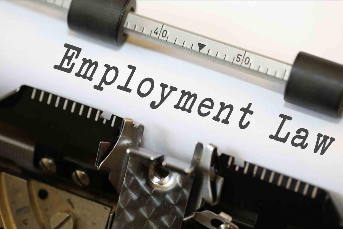 A close up image of a piece of paper secured to the platen of an old fashioned typewriter. The measuring bar is between 4|0 and 5|0 as it secures the paper in place with plastic rollers. Seemingly freshly struck by the typewriter is the words "Employment Law" in a classic typewriter font.